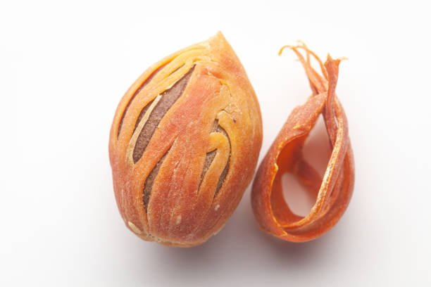 Macro close-up of Organic mace with nutmeg seed   (Myristica fragrans) on white background. Pile of Indian Aromatic Spice. Top view