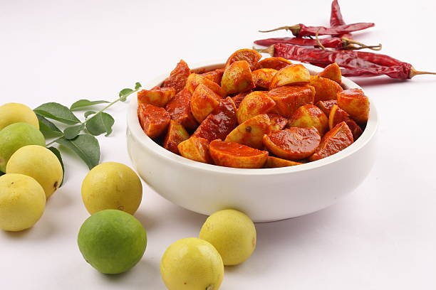 Ripe limes with bowl of spicy lime pickle.